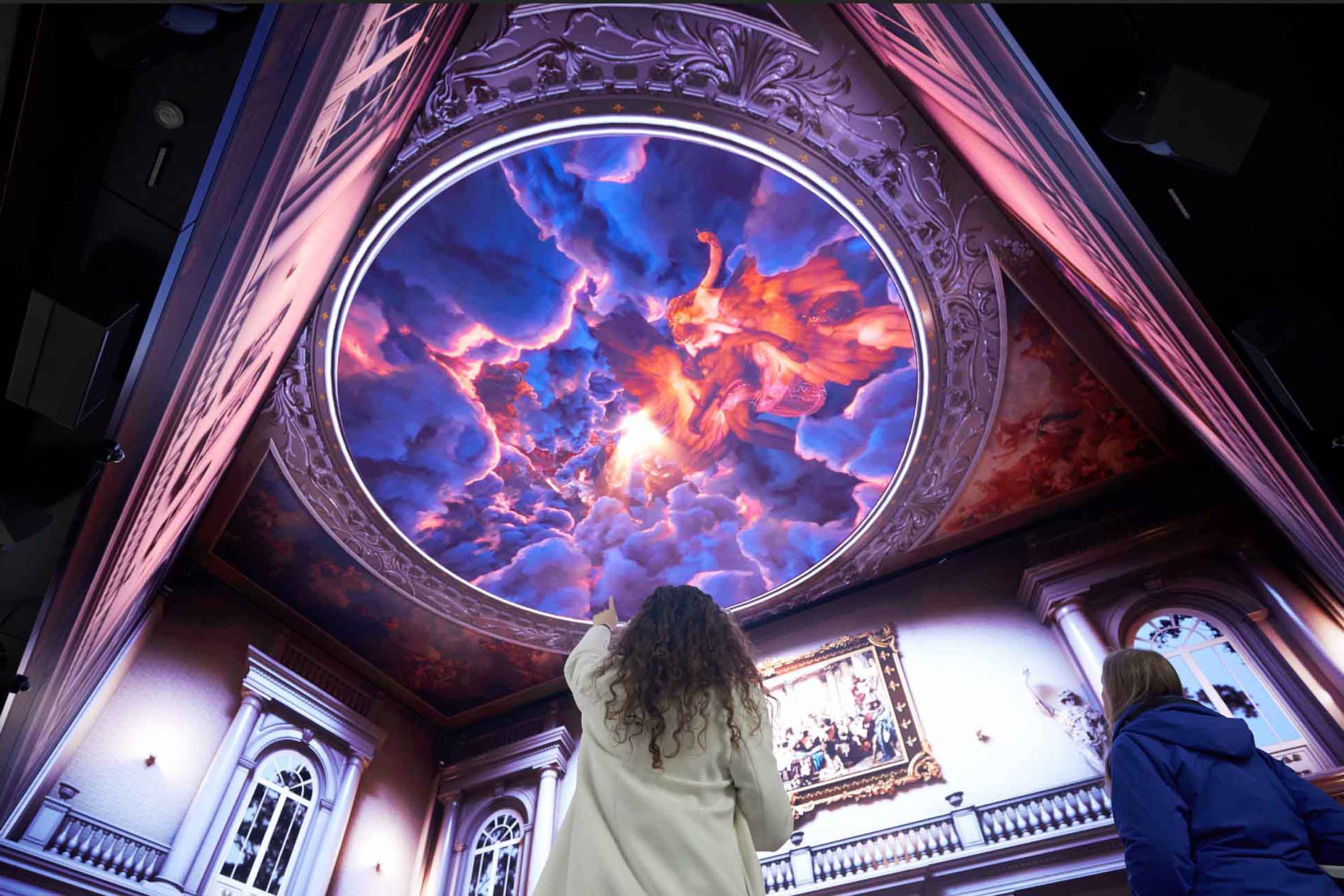 A visitor pointing up to the ceiling inside an immersive experience